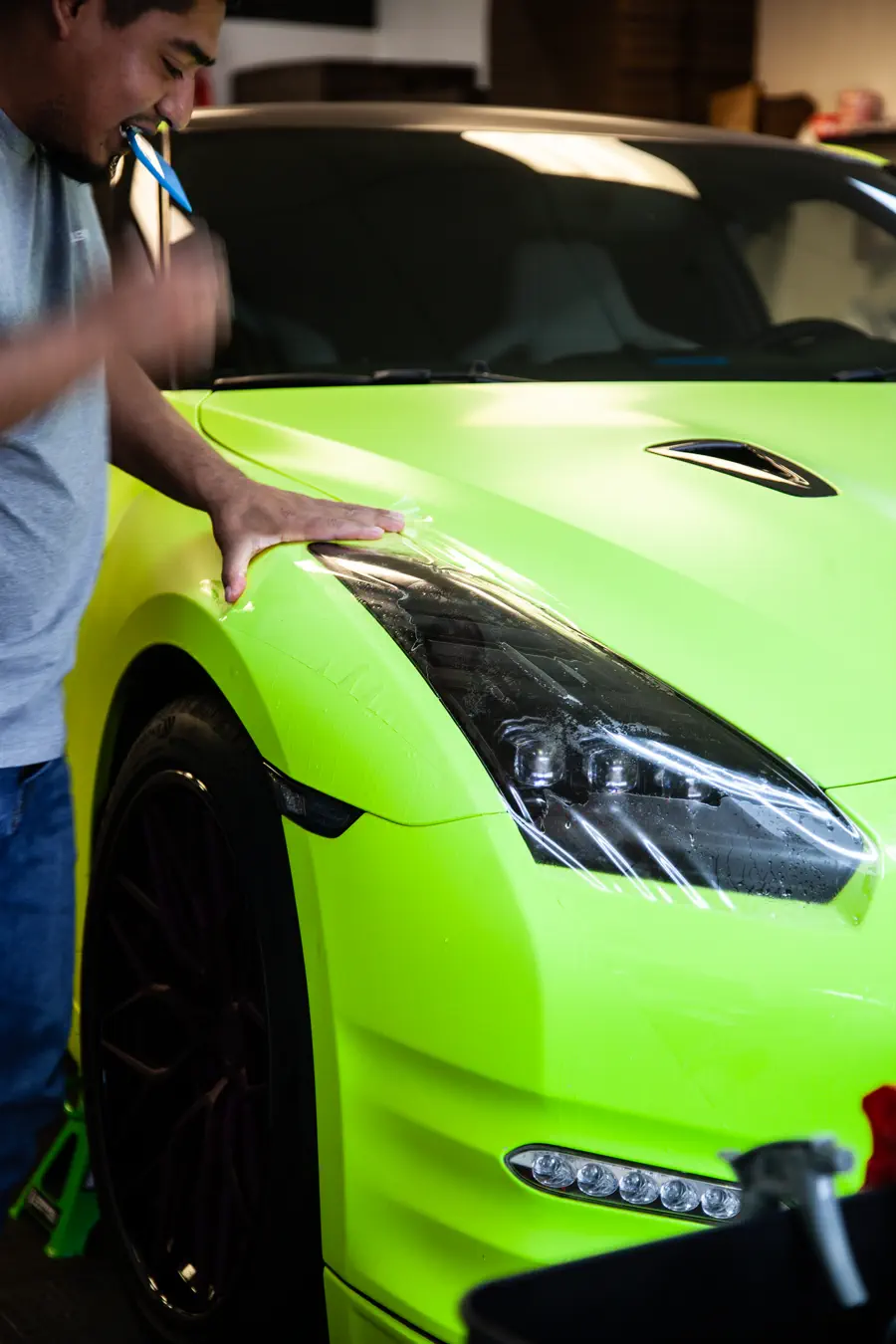 Headlight protection film being fitted on a lime green Nissan GT-R