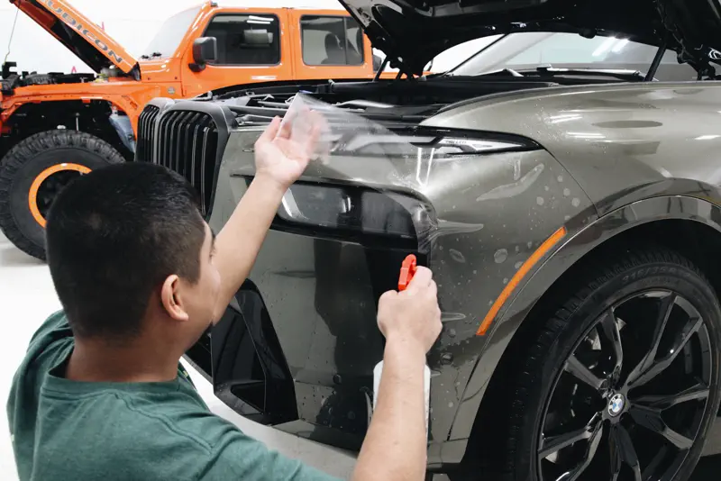 Paint protection film being applied to a BMW X7 front end
